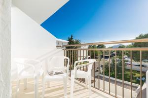 uma varanda com cadeiras brancas e vista para o oceano em Hotel Moré em Alcudia