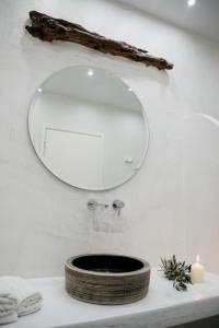 uma casa de banho com um espelho numa parede branca em Manthos Place em Mylopotas