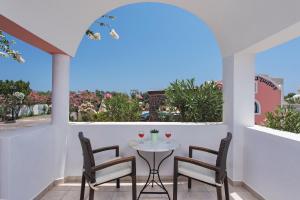 d'une terrasse avec une table, des chaises et une fenêtre. dans l'établissement Arapiou Apartments, à Perivolos