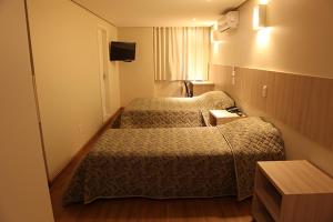 a hotel room with two beds and a television at Golden Hotel - O MAIS CENTRAL - Pet Friendly in Chapecó