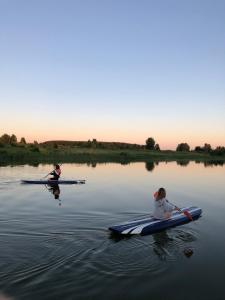 two people are kayaking on a body of water at Дом на реке in Chërnaya Zavod'