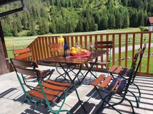 a wooden table with chairs and a bowl of fruit on a porch at De nussi's chalet 3 in Bach