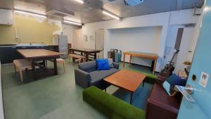 un soggiorno con divano, tavoli e chitarra di Iruka Hostel a Toyama
