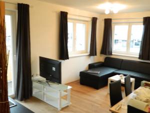 a living room with a black couch and a tv at Haus 4 Holidays in Bramberg am Wildkogel
