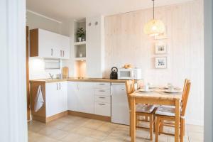 a kitchen with white cabinets and a table with chairs at Dom Rybaka apartament 4 in Ustka