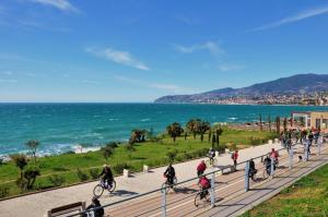 a group of people riding bikes down a sidewalk near the ocean at Sanremo Casa San Siro in Sanremo