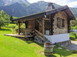 eine Holzhütte mit einem Fass im Gras in der Unterkunft Chalet Le Marmouzet in Les Houches