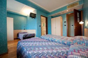 a hotel room with two beds and blue walls at Hotel Palavas in Villar Pellice