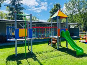 a playground with a slide in a park at Holiday Siesta Pensjonat, Domki in Rewal