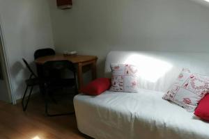 Un dormitorio con una cama con almohadas rojas y una mesa. en Studio mansardé 18 m2 climatisé avec piscine privée, en Gresse-en-Vercors