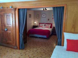 Schlafzimmer mit einem Bett mit roter Bettwäsche und blauen Vorhängen in der Unterkunft Chambres d'hôtes Sabine Billmann in Hunspach