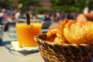 Apartments am Rheingarten في كولونيا: سلة من الخبز وكوب من عصير البرتقال