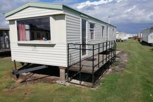 a tiny house sitting on a trailer in a field at Beachside, Family-friendly, WiFi, 8 berth Caravan 133 in Skegness