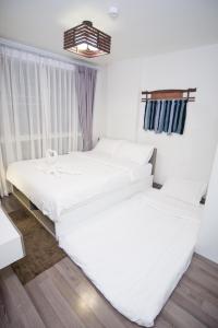 2 weiße Betten in einem Zimmer mit Fenster in der Unterkunft HOC2 Apartment Santitham Chiang Mai in Chiang Mai