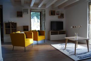 a living room with two yellow chairs and a television at Casa do cruceiro na Costa da Morte in Jornes