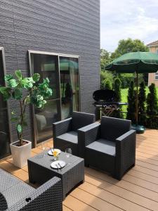 eine Terrasse mit 2 Stühlen, einem Tisch und einem Sonnenschirm in der Unterkunft KAI Ichinomiya in Ichinomiya