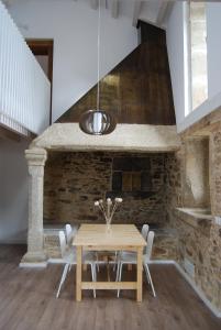 a dining room with a wooden table and a stone fireplace at Casa do cruceiro na Costa da Morte in Jornes