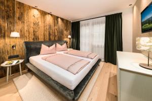 Un dormitorio con una cama grande con almohadas rosas. en Stadlhof, en Maria Alm am Steinernen Meer