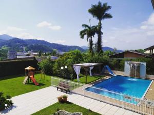 a backyard with a swimming pool and a playground at Pousada Harmonia Pomerana in Pomerode