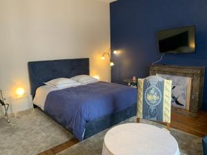 - une chambre avec un lit bleu et une télévision dans l'établissement La Maison des Sources à la Ferme d'Auxonnettes, à Auxonnettes