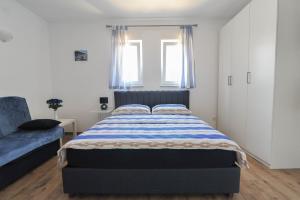 a bedroom with a bed and a blue couch at Apartmani Rebecca in Vir