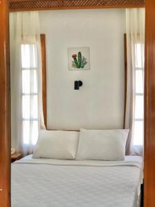 a bedroom with a bed with white sheets and two windows at Kekova Hotel in Kaş
