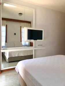 a bedroom with a bed and a tv on a wall at Kekova Hotel in Kaş