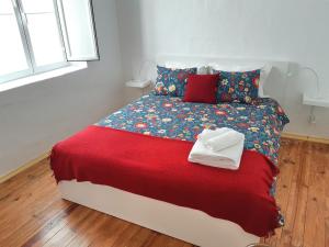 a bed that has a red blanket on it at Casas de Alcamim in Elvas