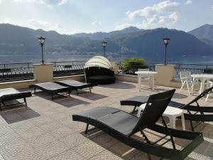 a patio with tables and chairs and a view of the water at Hotel Leon D'Oro in Orta San Giulio