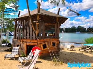 a small cabin on the beach with chairs and a swing at Unterkünfte bei Wake and Beach am Halbendorfer See in Schleife
