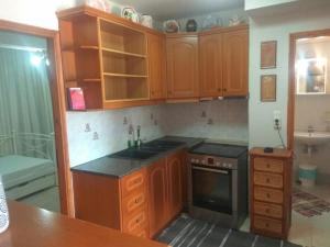 uma cozinha com armários de madeira, um lavatório e um fogão em Econa Residence em Poros