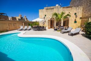einen Pool mit Stühlen und eine Terrasse in der Unterkunft Dar ta' Tumas in Għarb