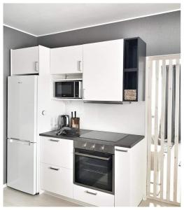 a white kitchen with a stove and a refrigerator at Gallen-Kallelankatu 5 in Pori