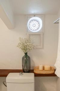 un jarrón de flores sentado en una mesa junto a una ventana en 971 Hotel Con Encanto, en Ciutadella