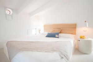 - une chambre blanche avec un grand lit et une tête de lit en bois dans l'établissement 971 Hotel Con Encanto, à Ciutadella