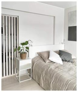 a white bedroom with a bed and a plant on a night stand at Gallen-Kallelankatu 5 in Pori