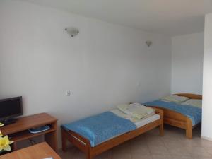 two beds in a room with a tv and a table at Pod Złotym Żaglem in Karwia