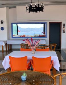 a dining room with a white table and orange chairs at Kekova Hotel in Kaş