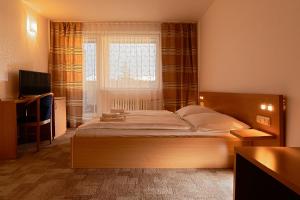 a bedroom with a bed in front of a window at Hotel Slezan in Bruntál