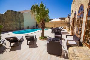 un patio con sillas, una piscina y una palmera en Dar ta' Tumas, en Għarb
