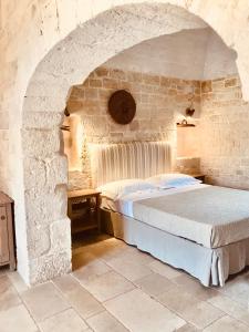 a bed in a room with a stone wall at Masseria Morrone in Ostuni