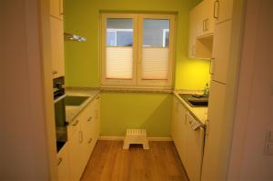 a kitchen with green walls and white cabinets and a small stool at Witt am See A in Klein Wittensee
