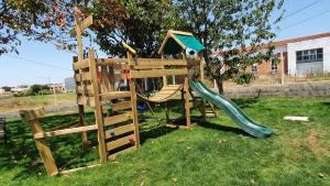 un parque infantil de madera con un tobogán y una casa en Cargal leiria, en Leiria