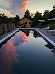 una piscina de agua con una puesta de sol en el cielo en Cascina Ghitin Relais, en Asti