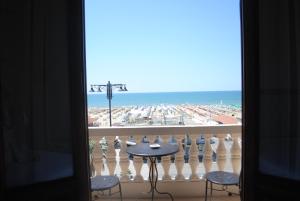 a view of the beach from a balcony with a table and chairs at Villa Tina in Viareggio