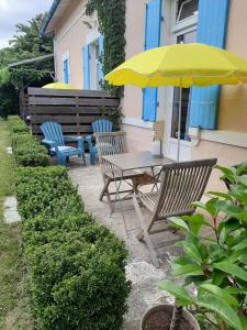 tavolo e sedie con ombrellone giallo di appartements d'hôtes La Foulonnerie a Mios