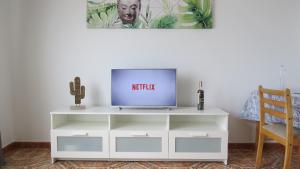 TV en un centro de entretenimiento blanco en una sala de estar en Apartamentos Orzola en Orzola