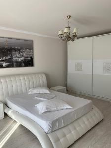 a white bedroom with a large white bed with a chandelier at Vila Pati in Ploieşti