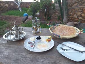 une table avec des assiettes de nourriture et une tarte dans l'établissement Hotel Leonor, à Had Beni Chiker