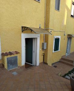 a yellow building with a door and an umbrella at A due passi dal castello in San Pio delle Camere